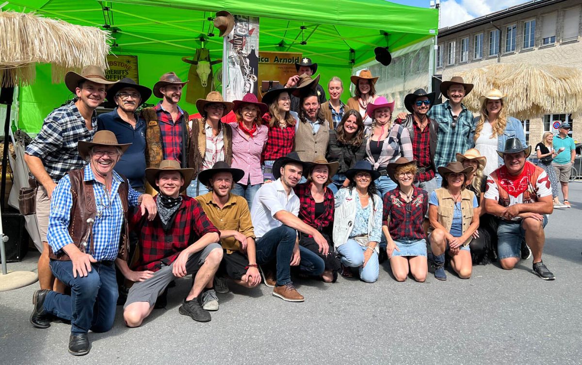 Teamfoto der Overtime Bar am Dorfmarkt in Arosa. Alle sind verkleidet und im Hintergrund sieht man die Bühne für die Band.