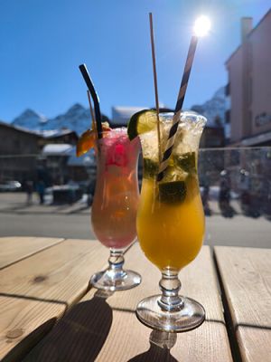 2 Cocktails auf der Terrasse der Overtime Bar bei schönstem Wetter. Blauer Himmel und die Sonne scheint.