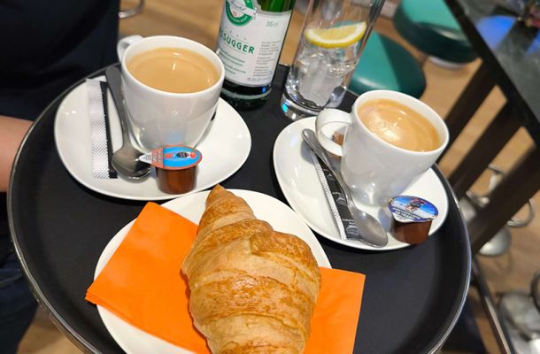 Kaffee, Gipfeli und Mineralwasser auf einem Tablet schoen angerichtet